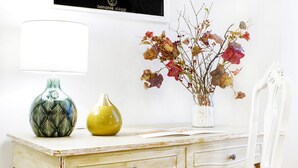 A white desk with two vases, one green and one yellow, and a vase with dried flowers. - GetTheKey San Vitale Apartment (Bologna)