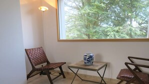 A room with a large window, two brown woven chairs, a small table with a blue and white ceramic vase, and a floor lamp. - Renovated house 100m from sea with WIFI, garden in Trégastel (Trégastel)