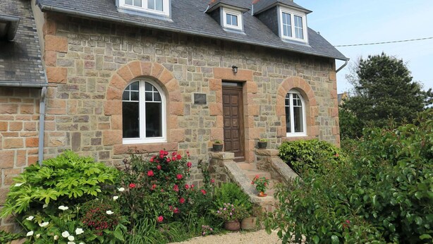 A stone house with a central entrance, two windows on the upper floor, and a small porch with potted plants. - Renovated house 100m from sea with WIFI, garden in Trégastel (Trégastel)