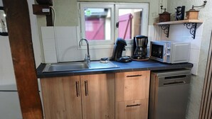 A compact kitchen with a sink, coffee maker, microwave, and dishwasher.