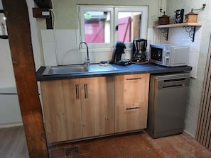 A compact kitchen with a sink, coffee maker, microwave, and dishwasher.