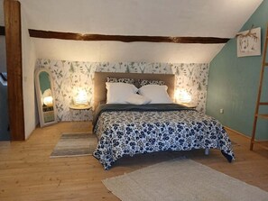 A bedroom with a bed, two bedside lamps, a wooden floor, and floral wallpaper. - Charming Family-Friendly Getaway with Garden, Mezzanine & Games Room in Arrou (Commune nouvelle d'Arrou)
