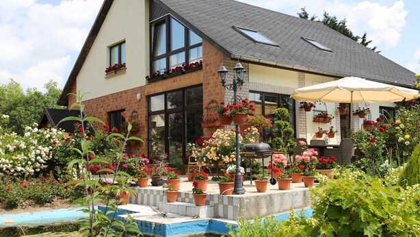 A two-story house with a brick facade, large windows, and a sloped roof. - Große Ferienwohnung Mitten im Grünen (Ziesendorf)