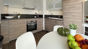 Eine moderne Küche mit Holzausstattung, einem eingebauten Backofen und einem weißen Esstisch mit Stühlen.