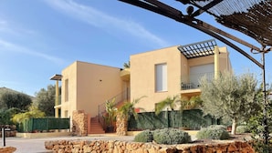 Ein modernes, zweistöckiges Haus mit einer Steinmauer, einer Treppe und einer Terrassenfläche.