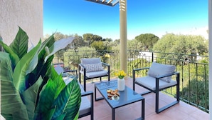 Ein Balkon mit zwei Stühlen, einem Tisch und einem Blumentopf.