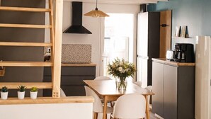 Eine Loft-Wohnung mit einer Holztreppe, einem Essbereich, einer Küche und einem Wohnraum mit Sofa und Lampe.