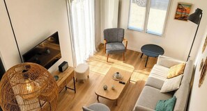 Un salon moderne avec un téléviseur, un canapé, un fauteuil et une table à manger.