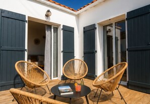 Une terrasse avec des fauteuils en osier, une table et un livre.