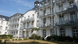 A multi-story hotel with balconies, a clock tower, and a garden area.
