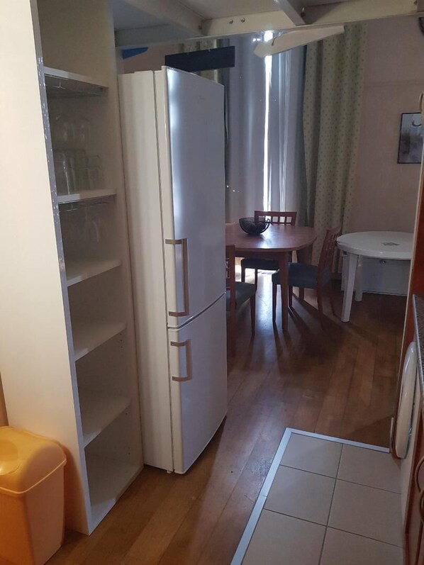 A compact kitchen with a white refrigerator, wooden dining table, and chairs.