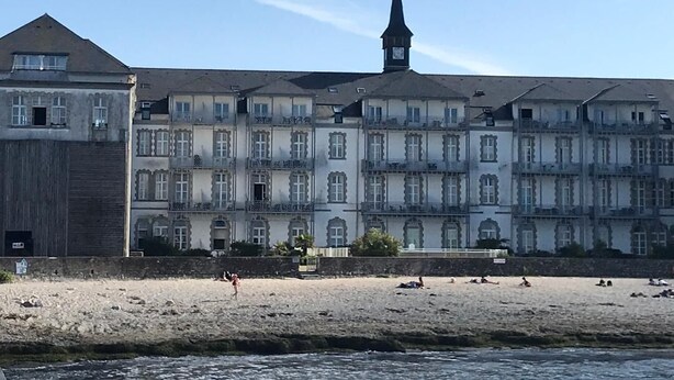 A waterfront building with multiple balconies and a church steeple.