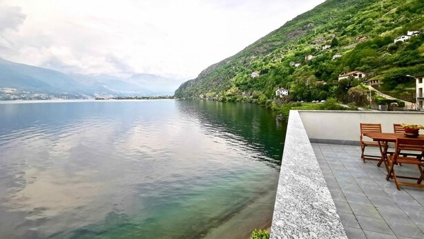 A lakeside terrace with a view of a mountain and a clear sky.