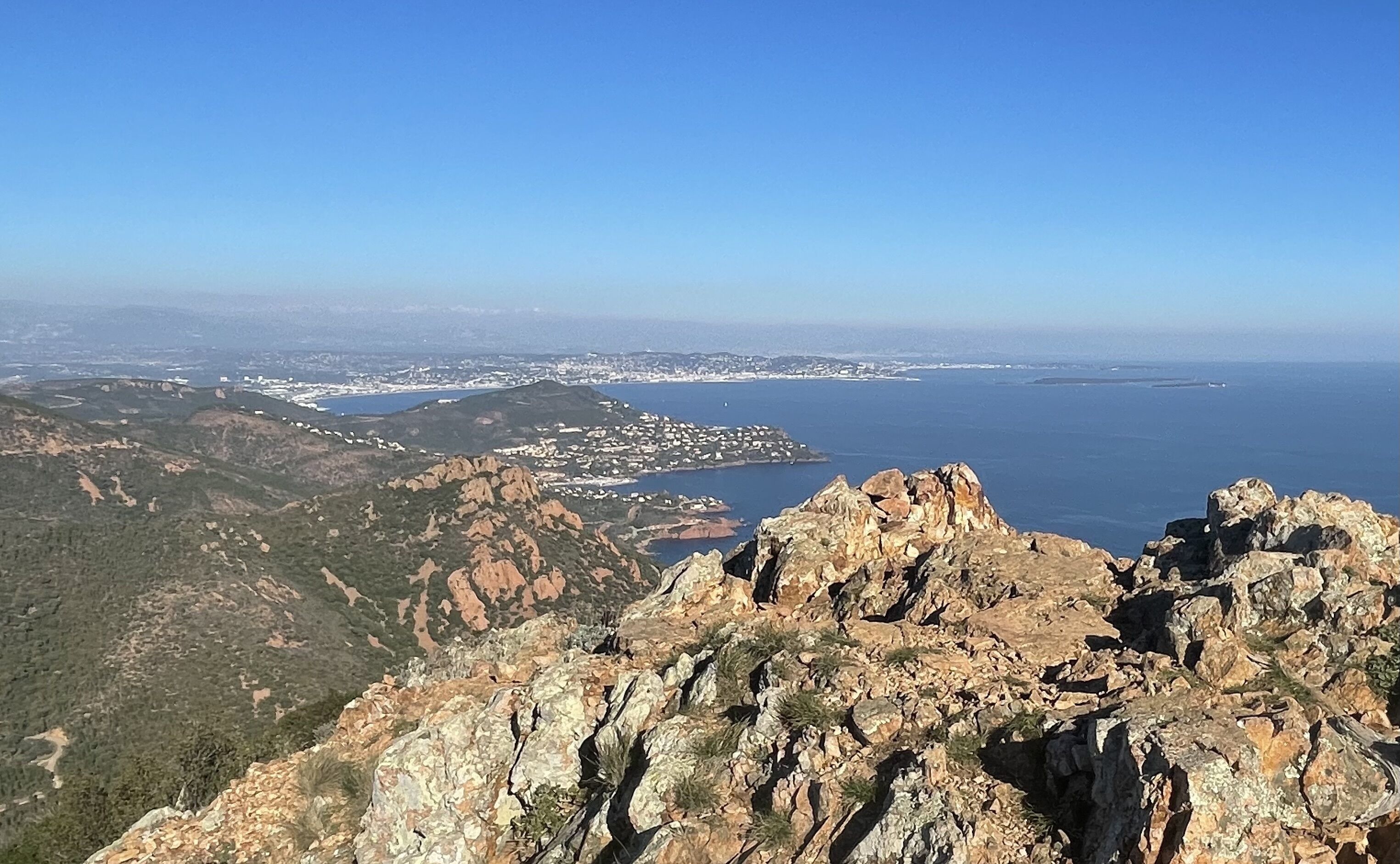 Un paisaje montañoso con terreno rocoso y una ciudad costera a lo lejos.