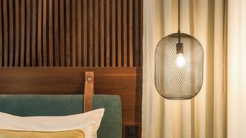 A hotel room with a bed, a nightstand, a telephone, and a hanging light fixture.