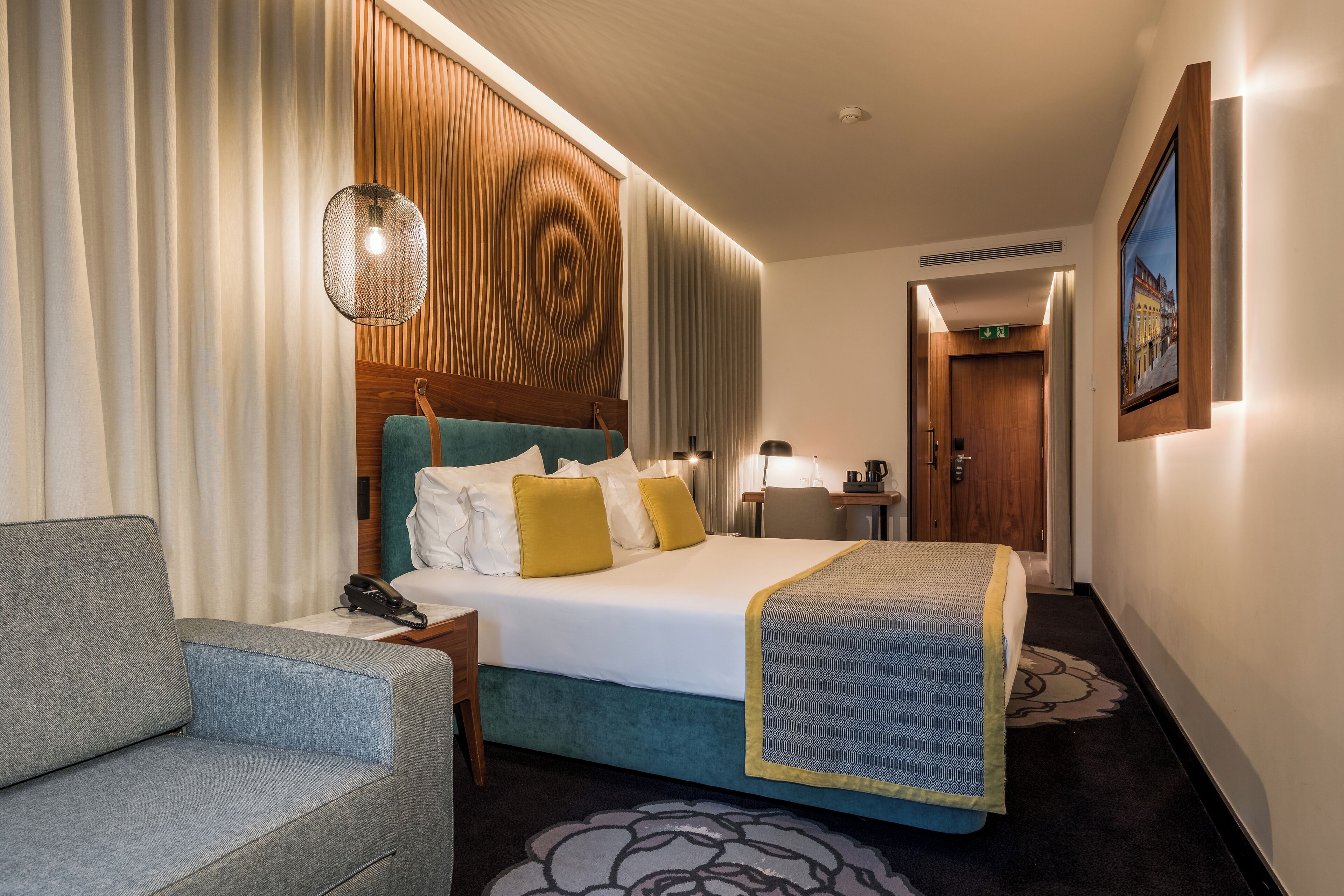 A hotel room with a bed, a sofa, a desk, and a bathroom door.