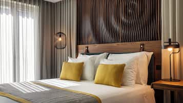 Una habitación de hotel moderna con un cabecero de madera, una manta con estampado y una lámpara de noche.