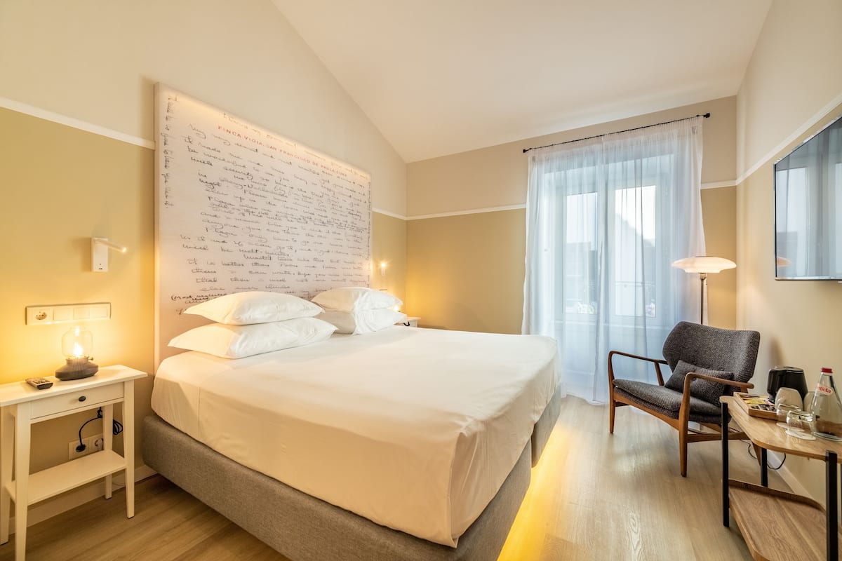 Ein Hotelzimmer mit einem großen Bett, einem Nachttisch, einem Sessel und einer Wand mit handgeschriebenen Notizen.