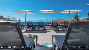 A terrace with outdoor seating, umbrellas, and a view of the sea. - Pestana Fisherman Village (Camara de Lobos)