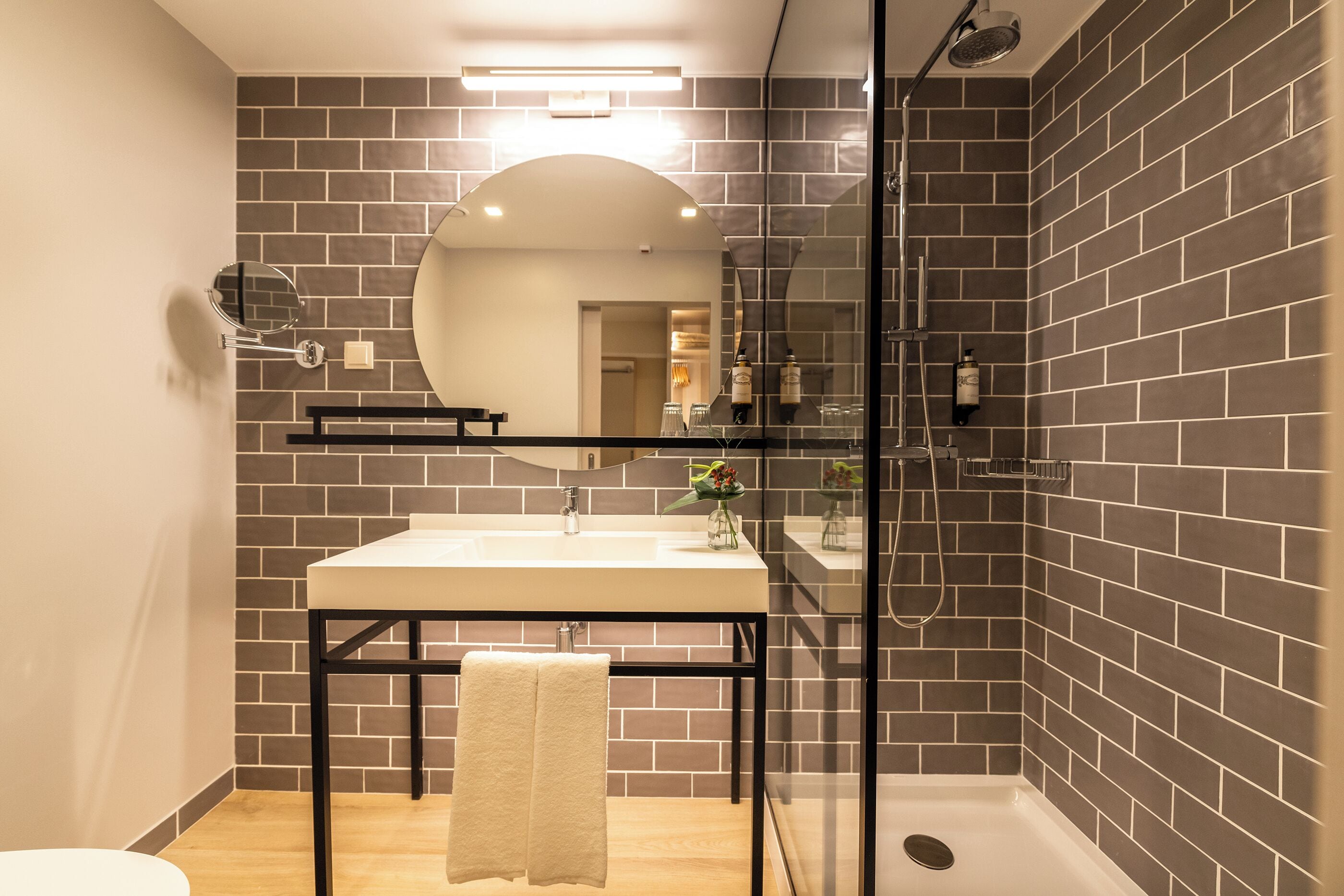 Un bany modern amb un mirall gran, un lavabo i una cabina de dutxa de vidre.