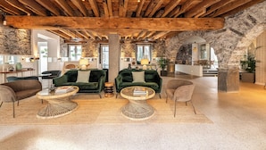 A spacious living area with a high wooden ceiling, stone walls, and a cozy seating arrangement including two green sofas and a coffee table. - Pestana Fisherman Village (Camara de Lobos)