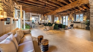 A spacious living area with a high ceiling, stone walls, and a mix of seating arrangements including a sofa and chairs. - Pestana Fisherman Village (Camara de Lobos)