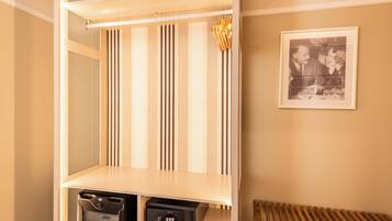 Une pièce avec une armoire à portes miroir, un cadre avec une photographie accroché au mur et un petit coffre-fort posé sur le sol.