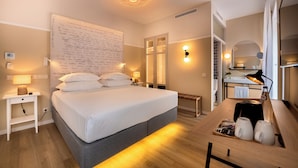 A modern hotel room with a large bed, bedside lamps, a wooden desk with a lamp, a mirror, and a wall with handwritten notes. - Pestana Fisherman Village (Camara de Lobos)