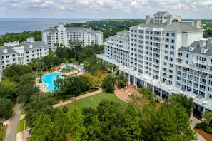 A multi-story hotel with a central swimming pool surrounded by lush greenery.
