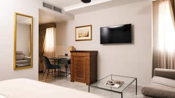 Habitación de hotel con una cama, un escritorio con silla, televisión, armario y una mesita de café.