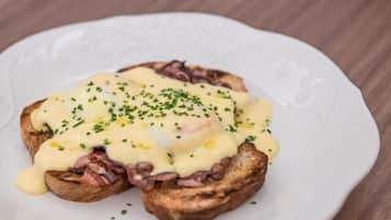 En tallerken med en sandwich toppet med æg og purløg.