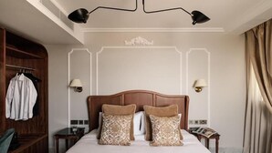 Een hotelkamer met een groot bed, twee bedlampen, een houten hoofdeinde, een garderobe en een nachtkastje met een lamp.