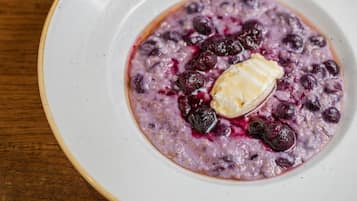 Un tazón de avena con arándanos y un poco de mantequilla encima.