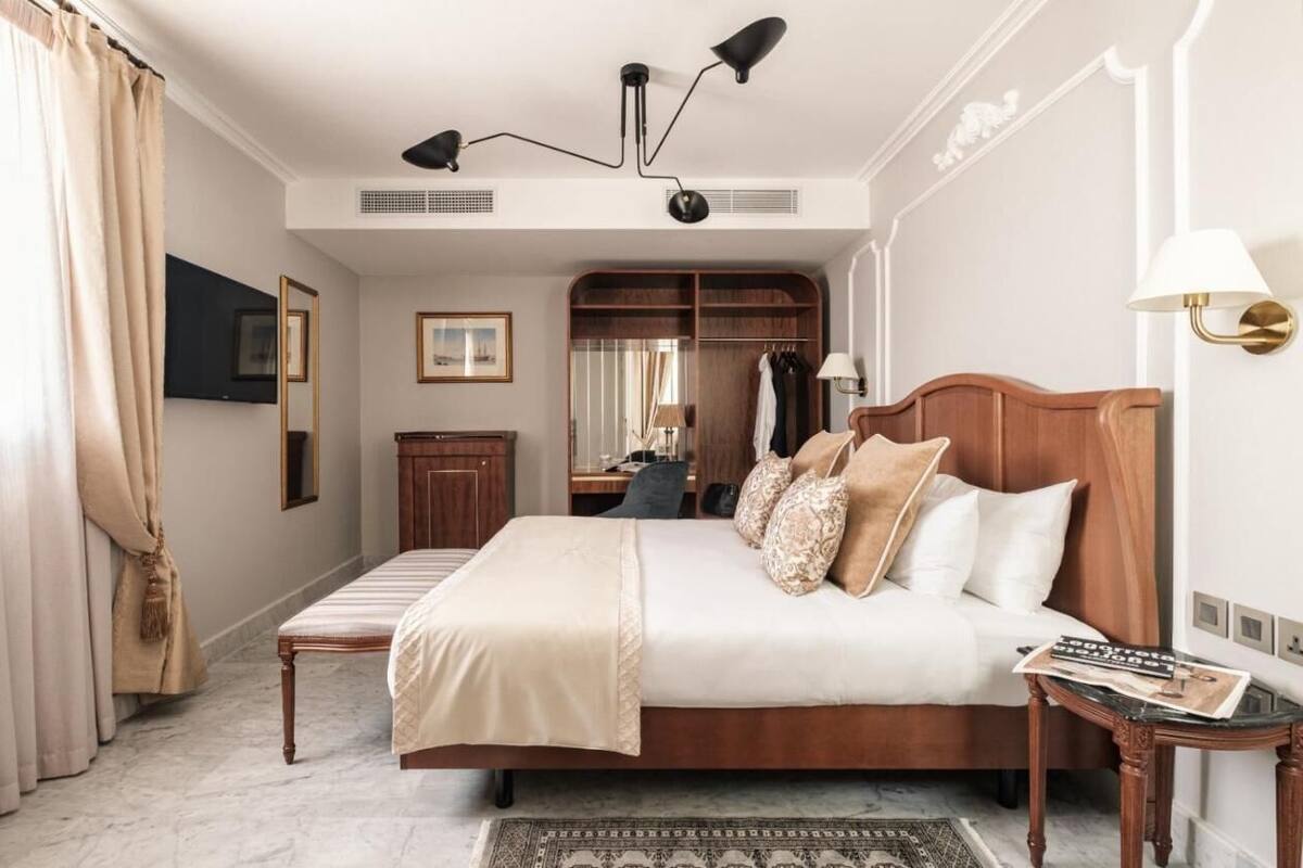 Un dormitorio espacioso con una cama grande, un cabecero de madera, una mesita de noche, un armario y un espejo.