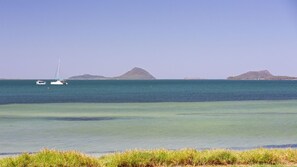 Eine Küstenlandschaft mit zwei Segelbooten auf ruhigem Wasser, umgeben von kleinen Inseln.