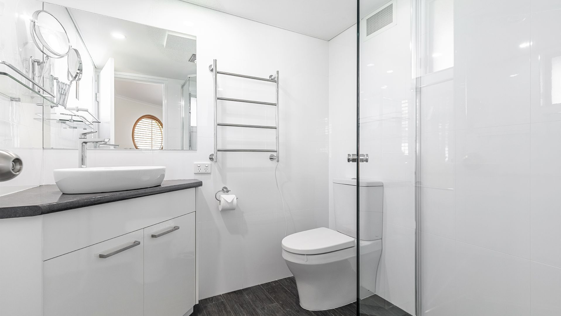 Ein modernes Badezimmer mit Waschbecken, Spiegel und Toilette in Weiß.