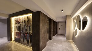Un pasillo moderno con un gran panel iluminado en la pared, piso de baldosas limpias y una puerta con la etiqueta "501".
