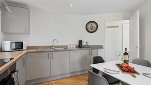 A modern kitchen with a microwave, sink, and dining area with a table set for two.