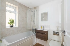 A modern bathroom with a glass-enclosed shower, a standalone bathtub, a vanity with a mirror, and a potted plant by the window. - Hawthorn - Oxford (Oxford)