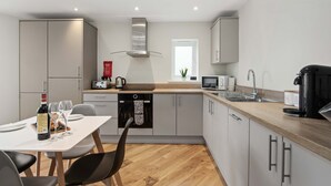 A modern kitchen with a dining area, featuring a built-in oven, microwave, and kettle.