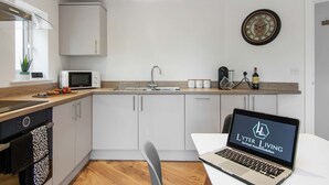 A modern kitchen with white cabinets, a microwave, a sink, and a laptop displaying 'Lytter Living'.