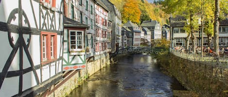 A narrow waterway flanked by traditional half-timbered buildings with a stone bridge overhead.