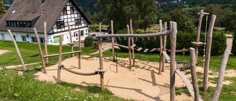 Un parque infantil con estructuras de madera y una casa al fondo.