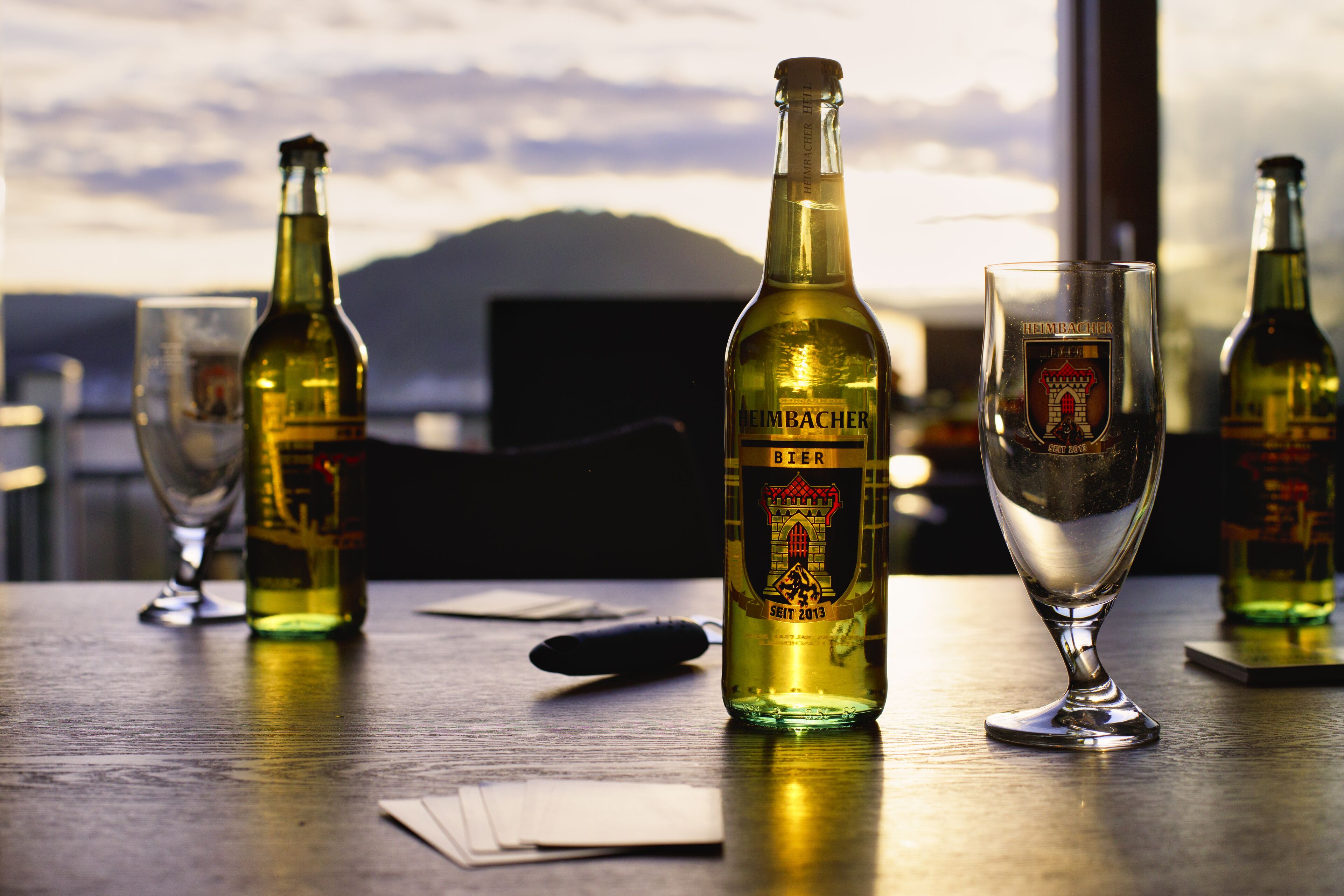 Une bouteille de bière et un verre sur une table, avec un paysage pittoresque en arrière-plan.