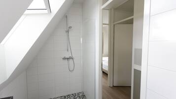 Um banheiro moderno com claraboia, chuveiro e piso revestido.