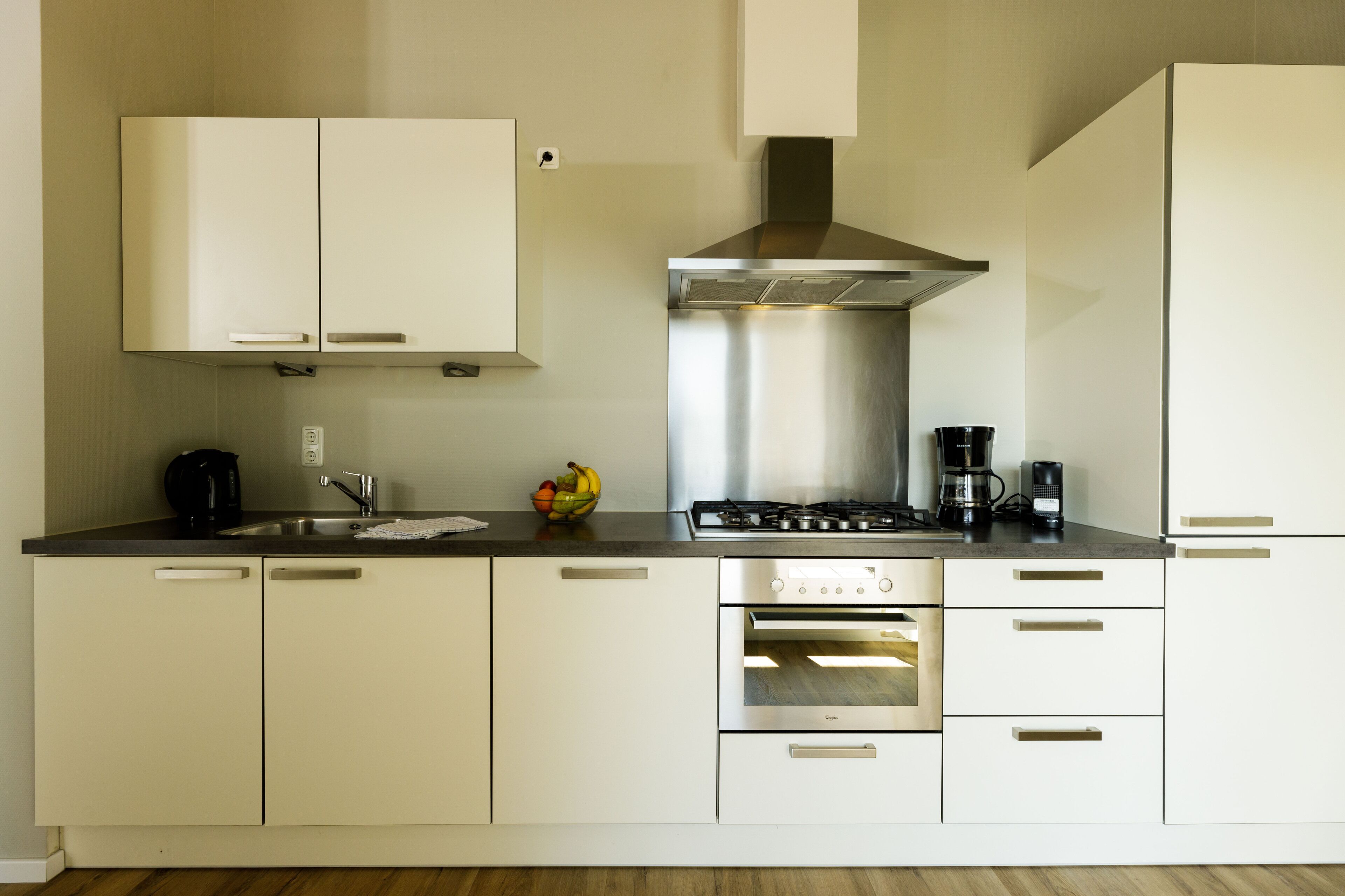 Una cocina moderna con armarios blancos, una estufa de acero inoxidable y un horno.