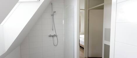 A modern bathroom with a skylight, a shower with a handheld showerhead, and a tiled floor.