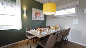 Un comedor con una mesa de madera dispuesta para el desayuno, rodeado de sillas.