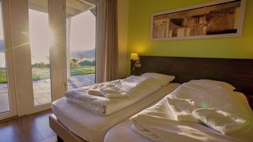 A hotel room with a bed, a painting on the wall, and a view of the outdoors.