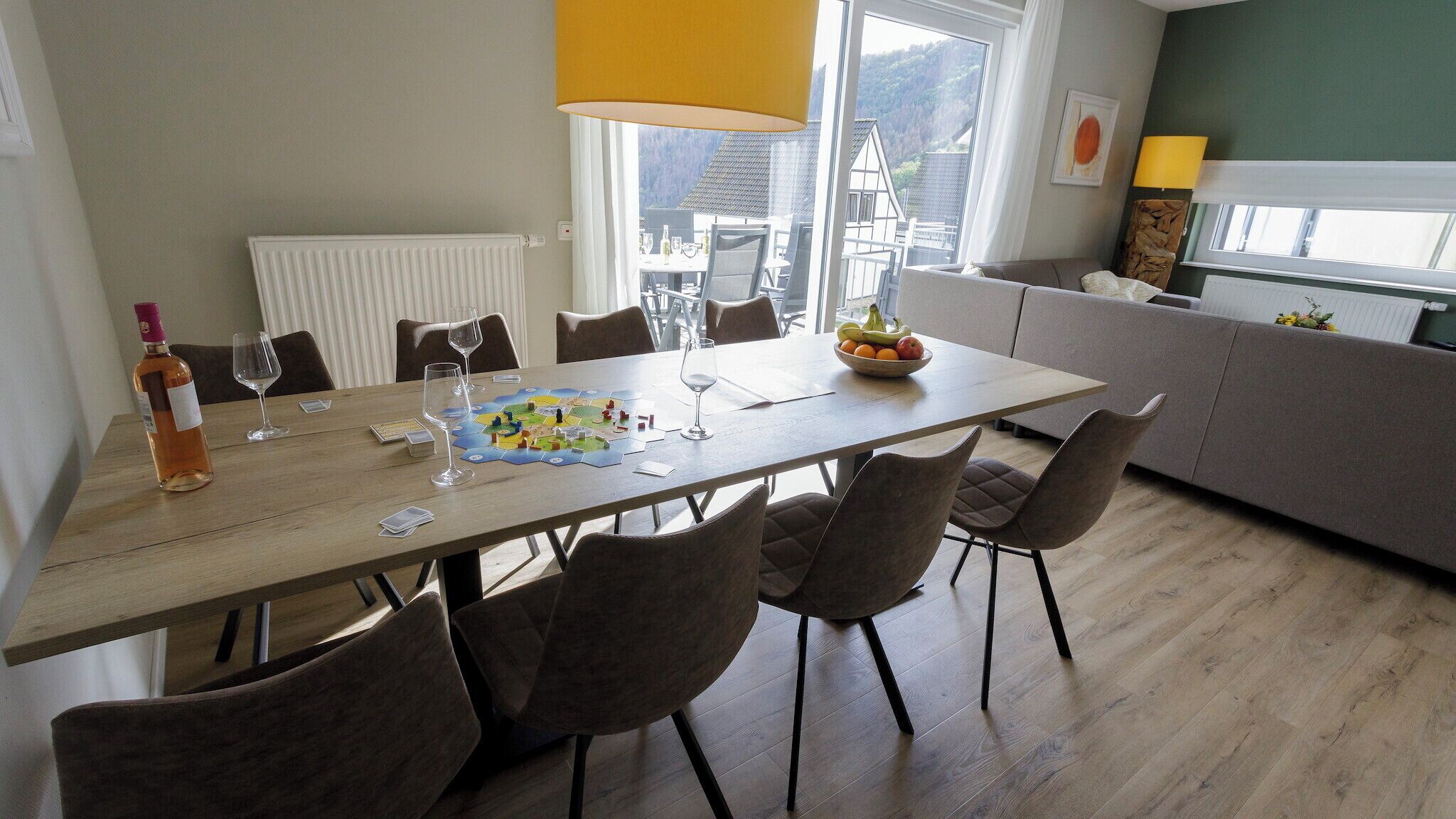 A dining area with a wooden table, chairs, and a bowl of fruit.